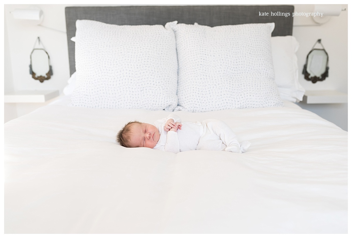 Newborn girl lies peacefully on white bed