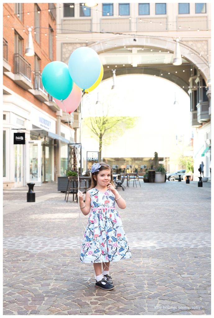 Young girl with balloons in alley